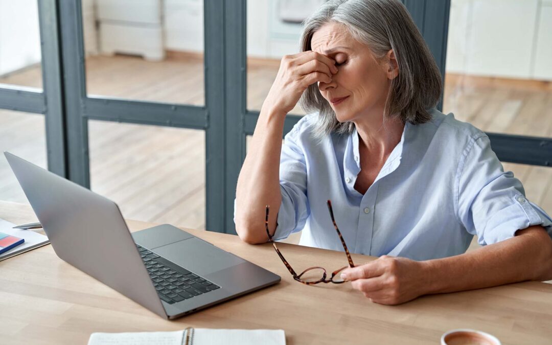 Overworked tired older lady holding glasses feeling headache, having eyesight problem after computer work. Stressed mature senior business woman suffering from fatigue rubbing dry eyes at workplace.